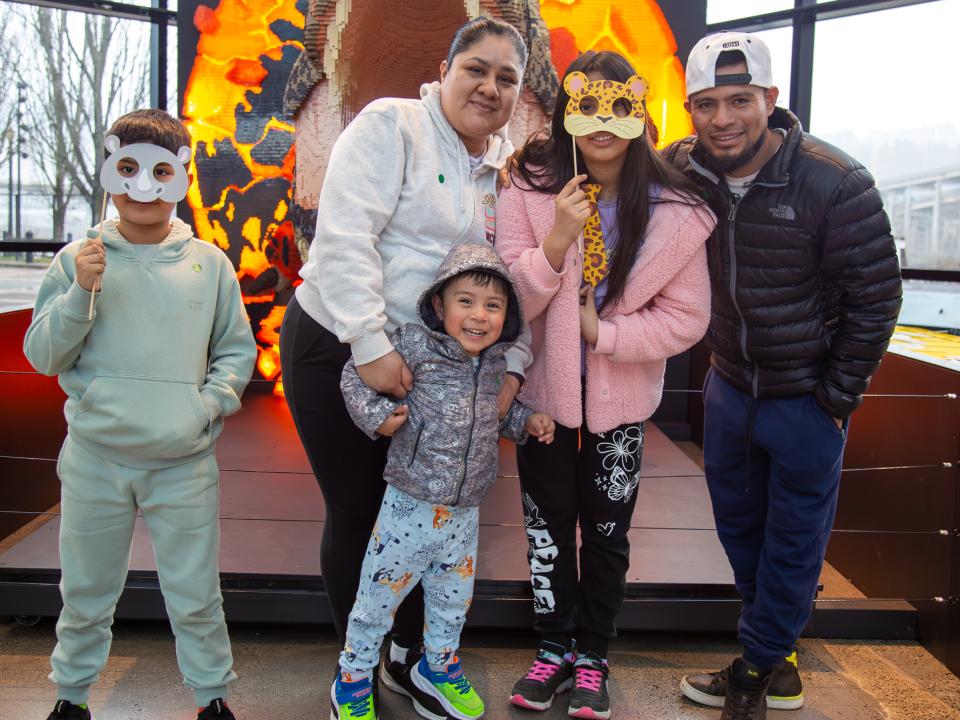 Family with preschool age child in front of Lego dinosaur at OMSI